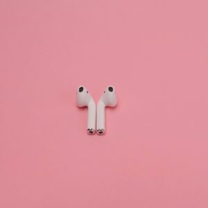 INICIO Modern wireless earbuds on a pastel pink background, showcasing minimal tech design.